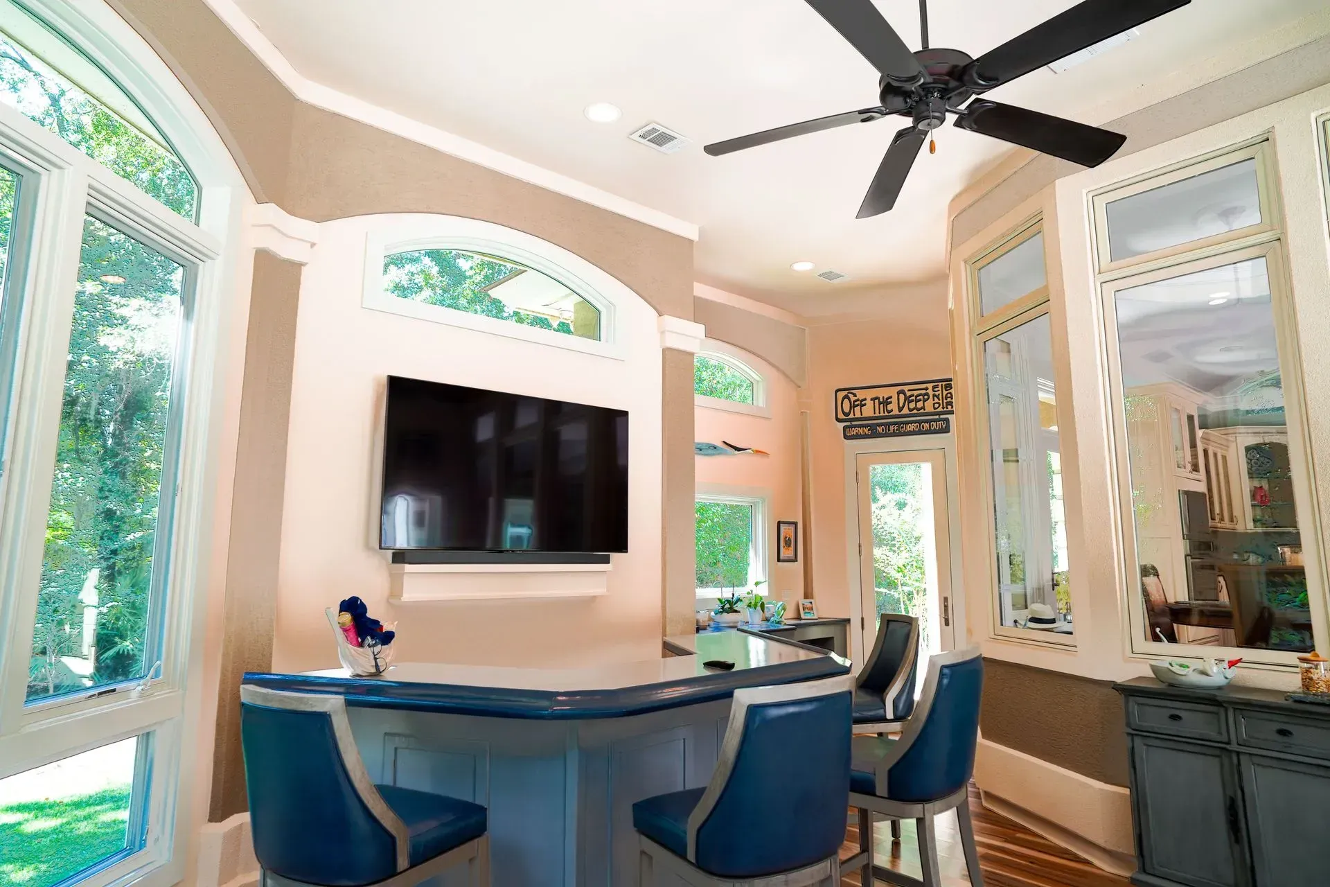 Bar area with blue stools, a TV, and large windows looking outside.