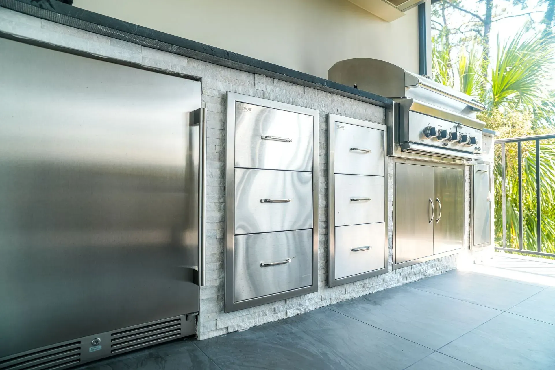 Outdoor kitchen with stainless steel appliances set into a white brick wall.