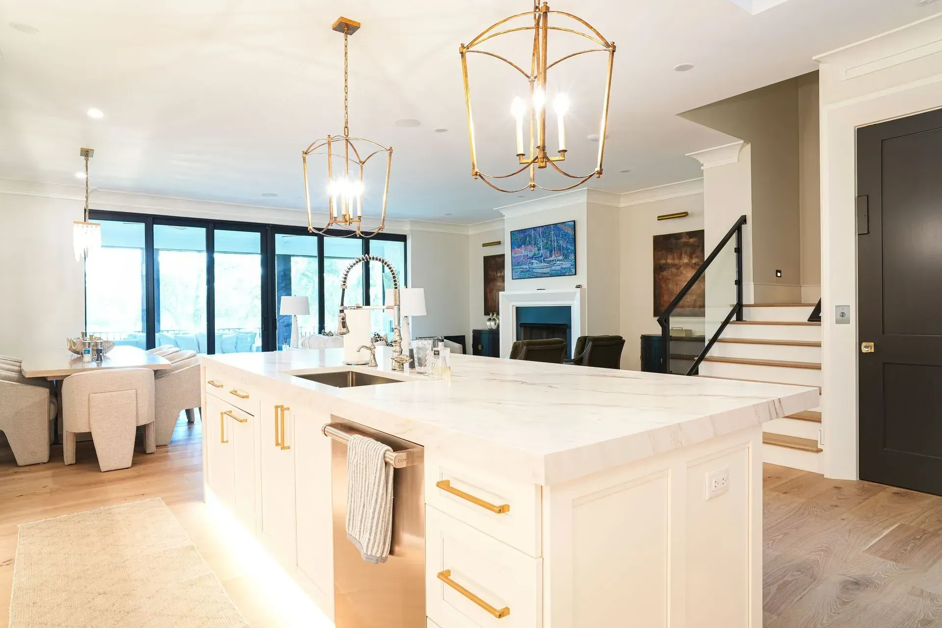 Modern kitchen with white island, gold light fixtures, and open to living room.