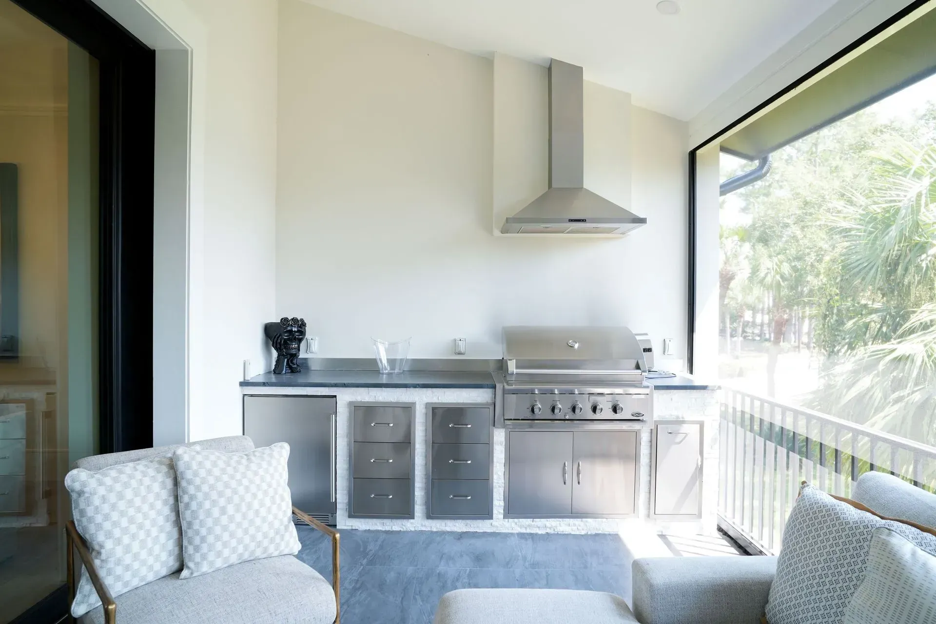 Outdoor kitchen with stainless steel appliances, neutral walls, and seating.