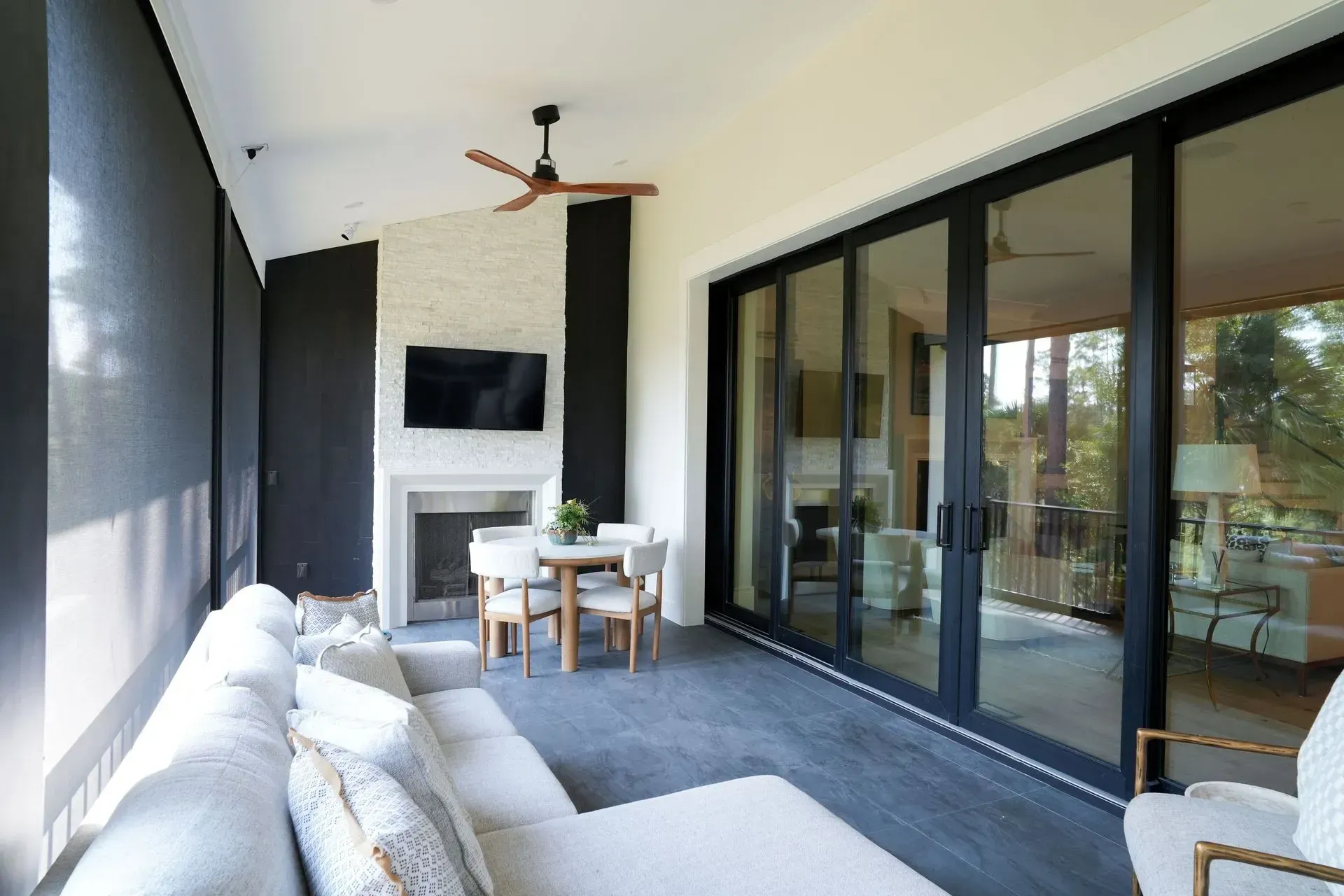 Outdoor living room with fireplace, sliding glass doors, sectional sofa, and dining table.