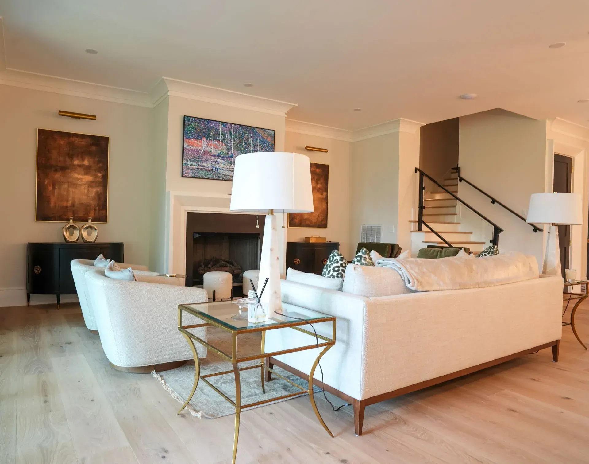 Living room with white sofas, fireplace, and gold accent furniture.