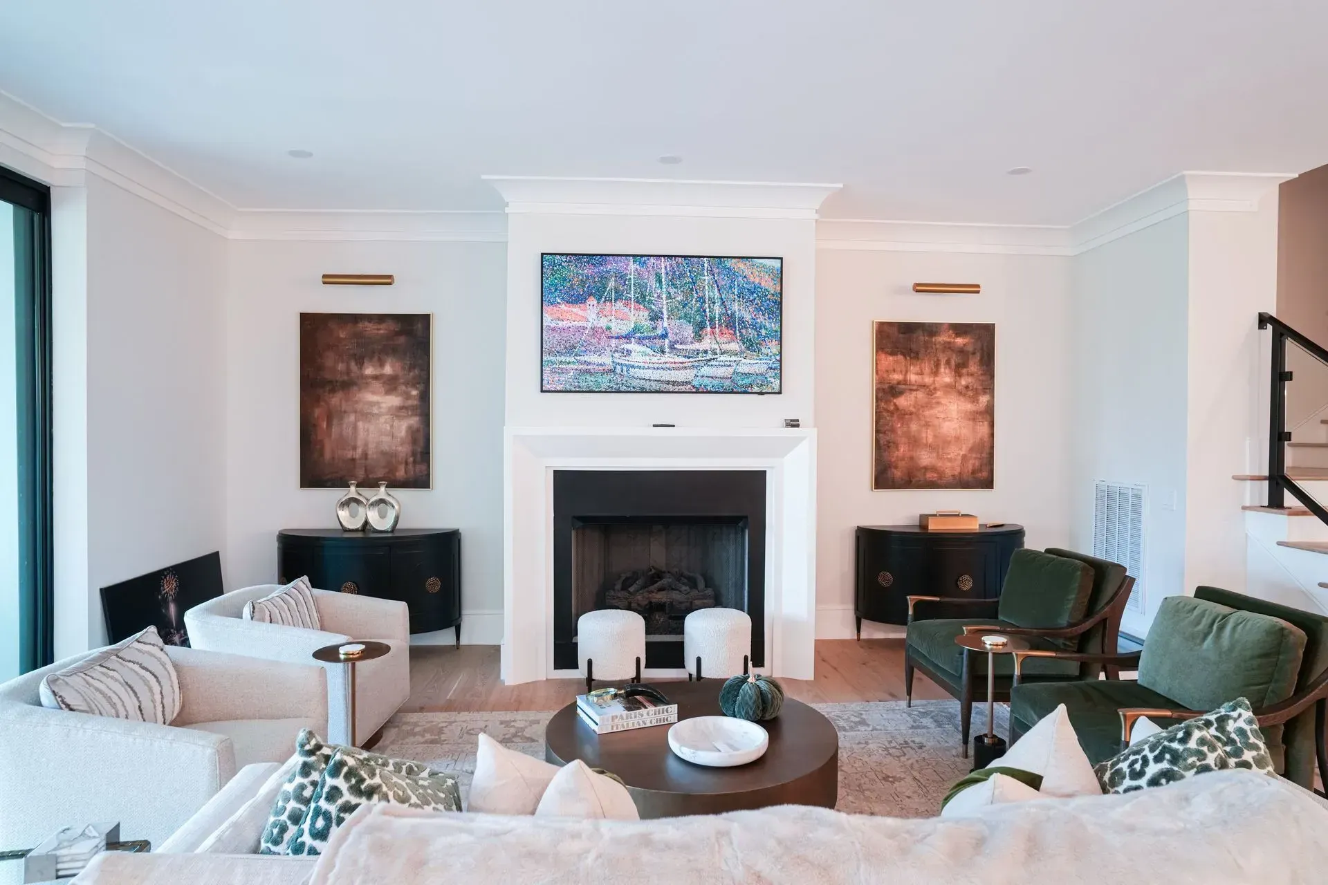 Living room with fireplace, white walls, and dark accents. Artwork, couches, and a coffee table are present.
