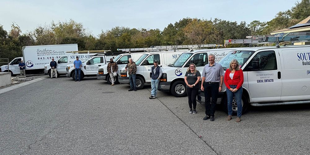 A group of people standing in front of white vans with company logos.