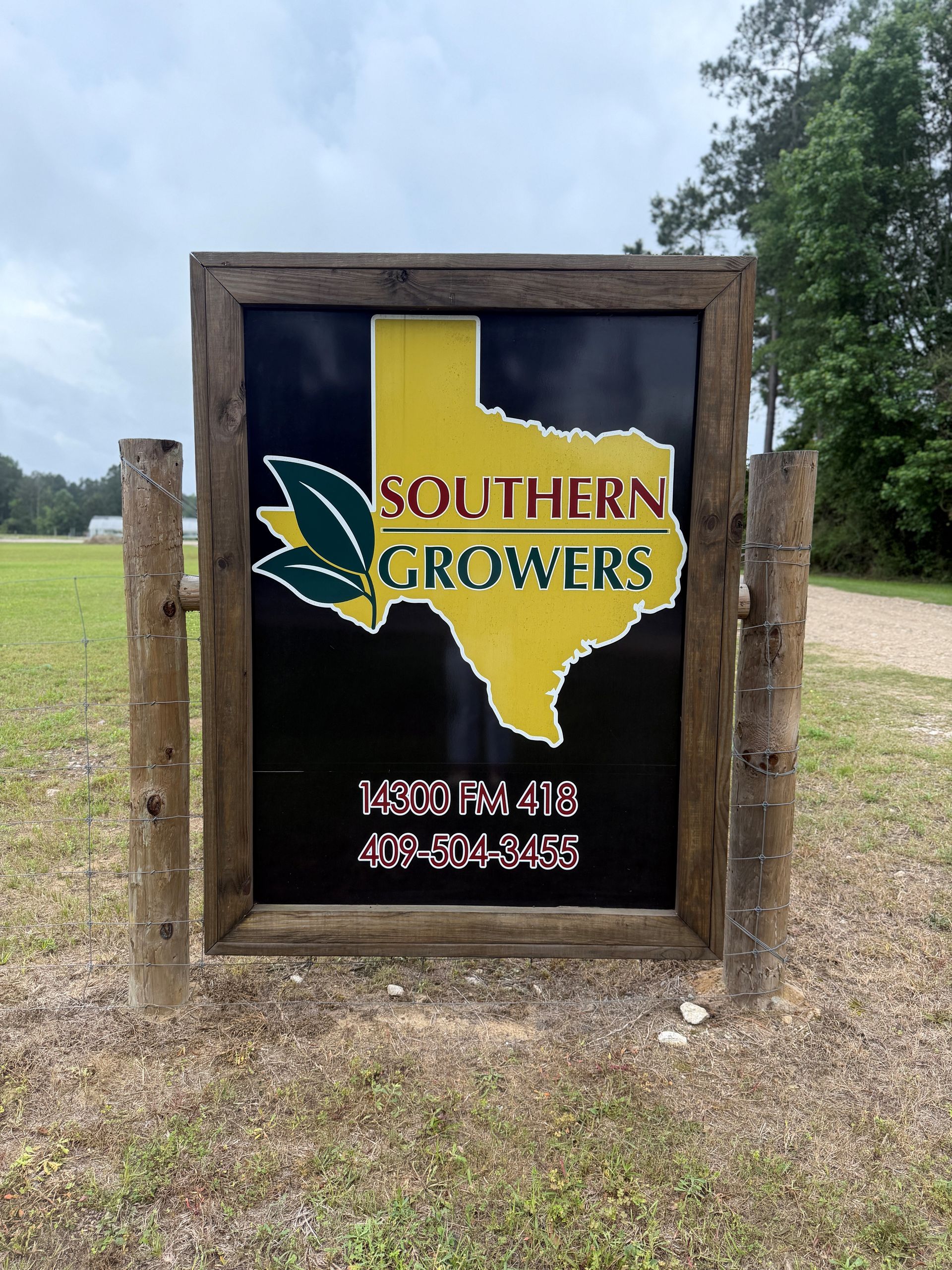 Southern Growers roadside sign with Texas outline logo in a wooden frame beside a grassy field