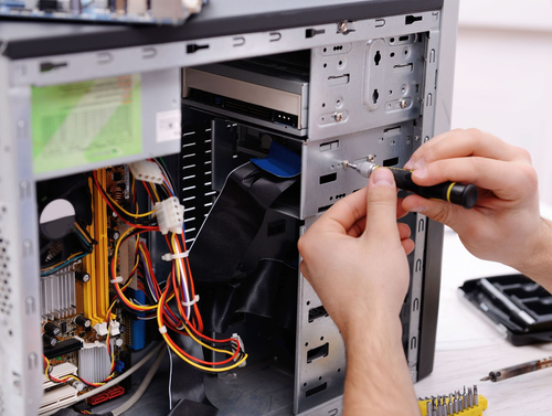 Hands working inside an open desktop computer case with visible wires and components.