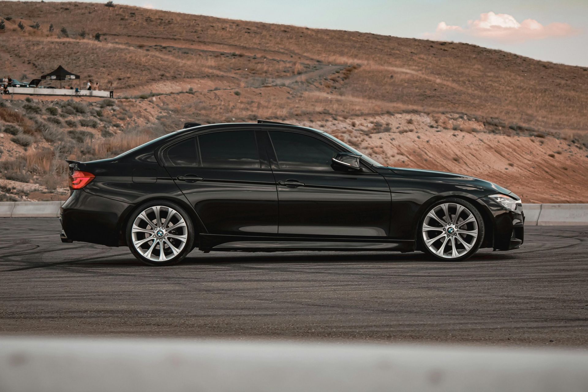 Black sedan parked on a road with a desert hillside in the background