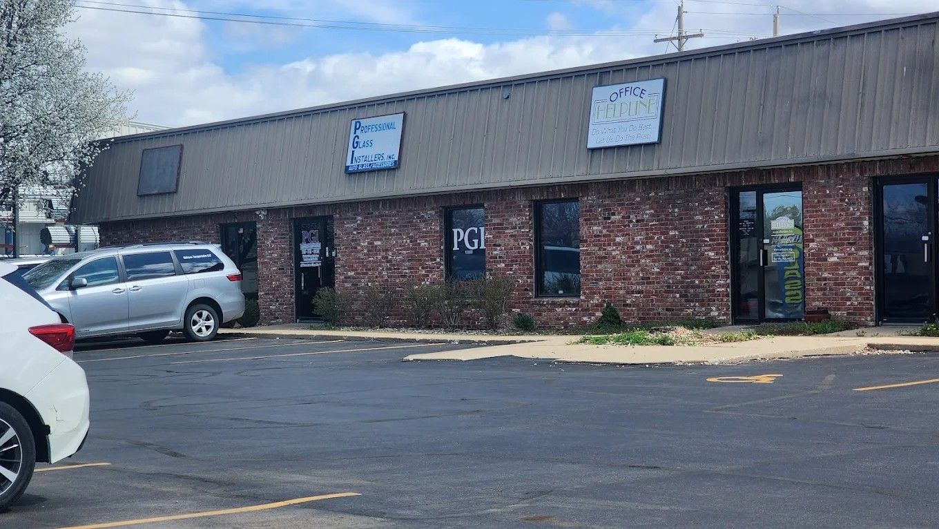 Brick strip mall with parked cars in a lot under a cloudy sky