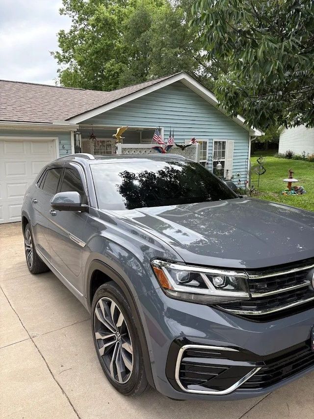 Gray SUV parked in a suburban driveway in front of a blue house with an American flag