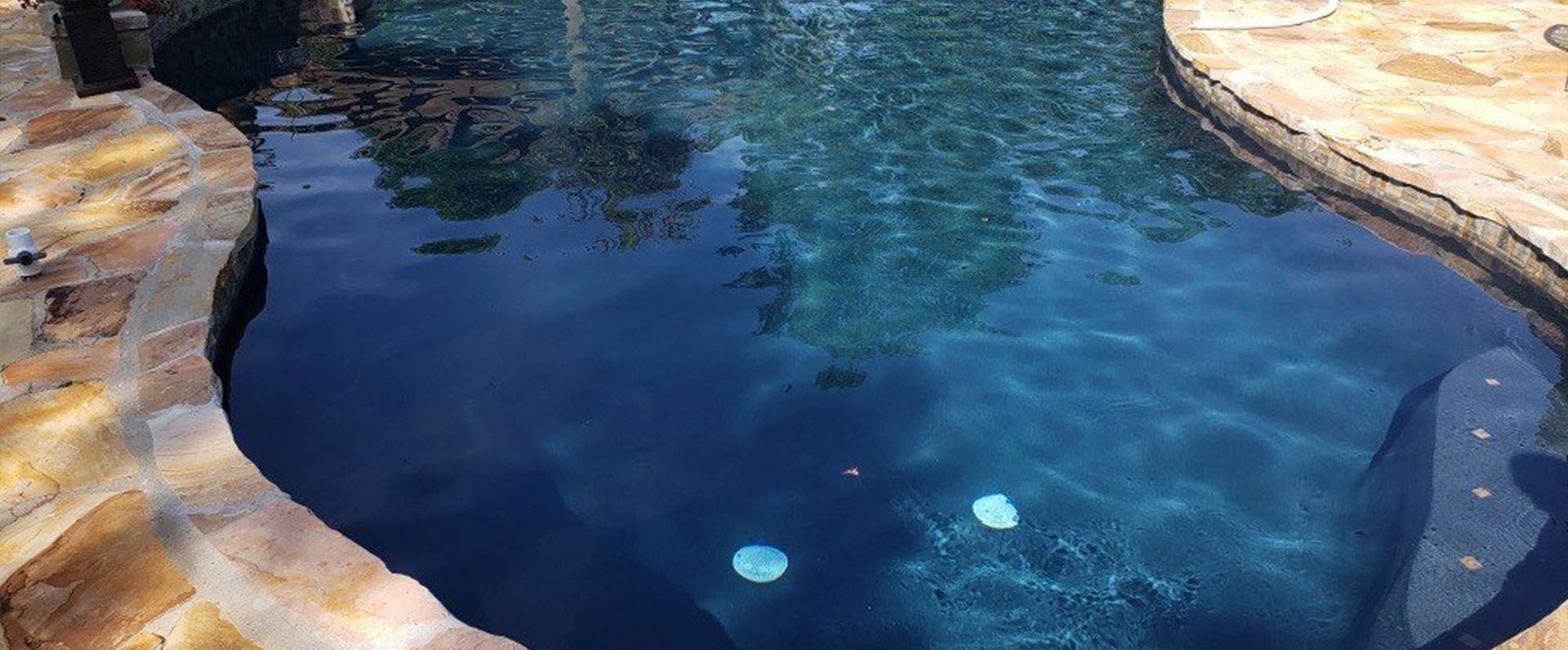 A large swimming pool filled with blue water and surrounded by rocks