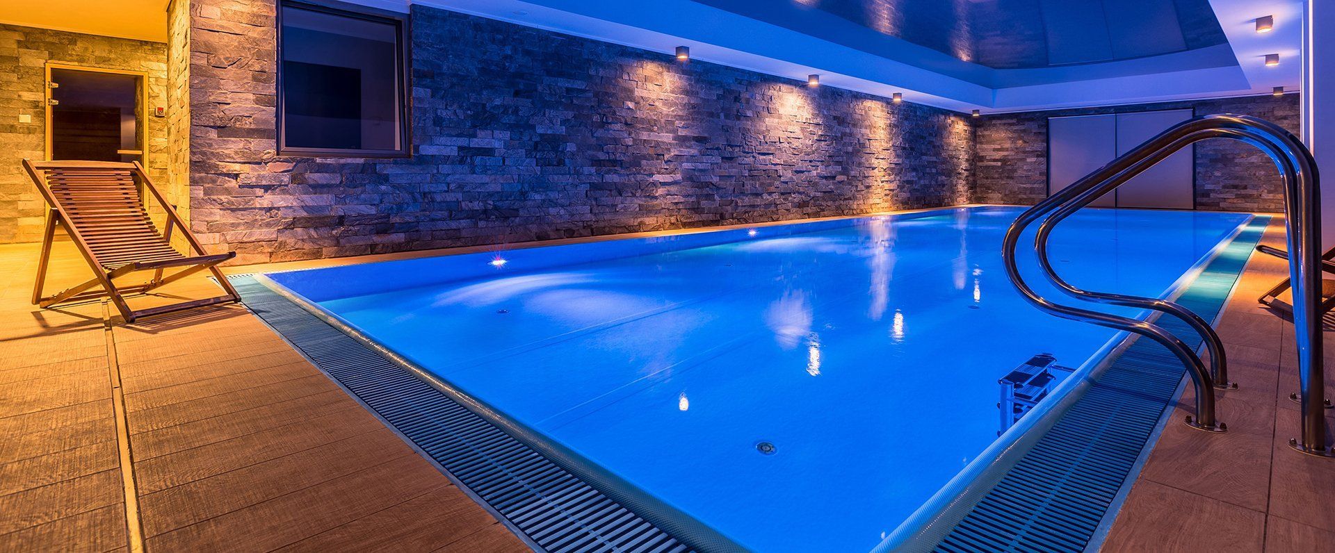 A large indoor swimming pool is lit up at night