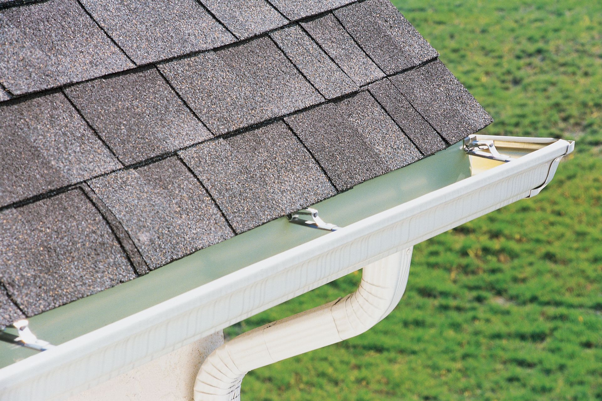 Gray roof shingles with white gutter and downspout.