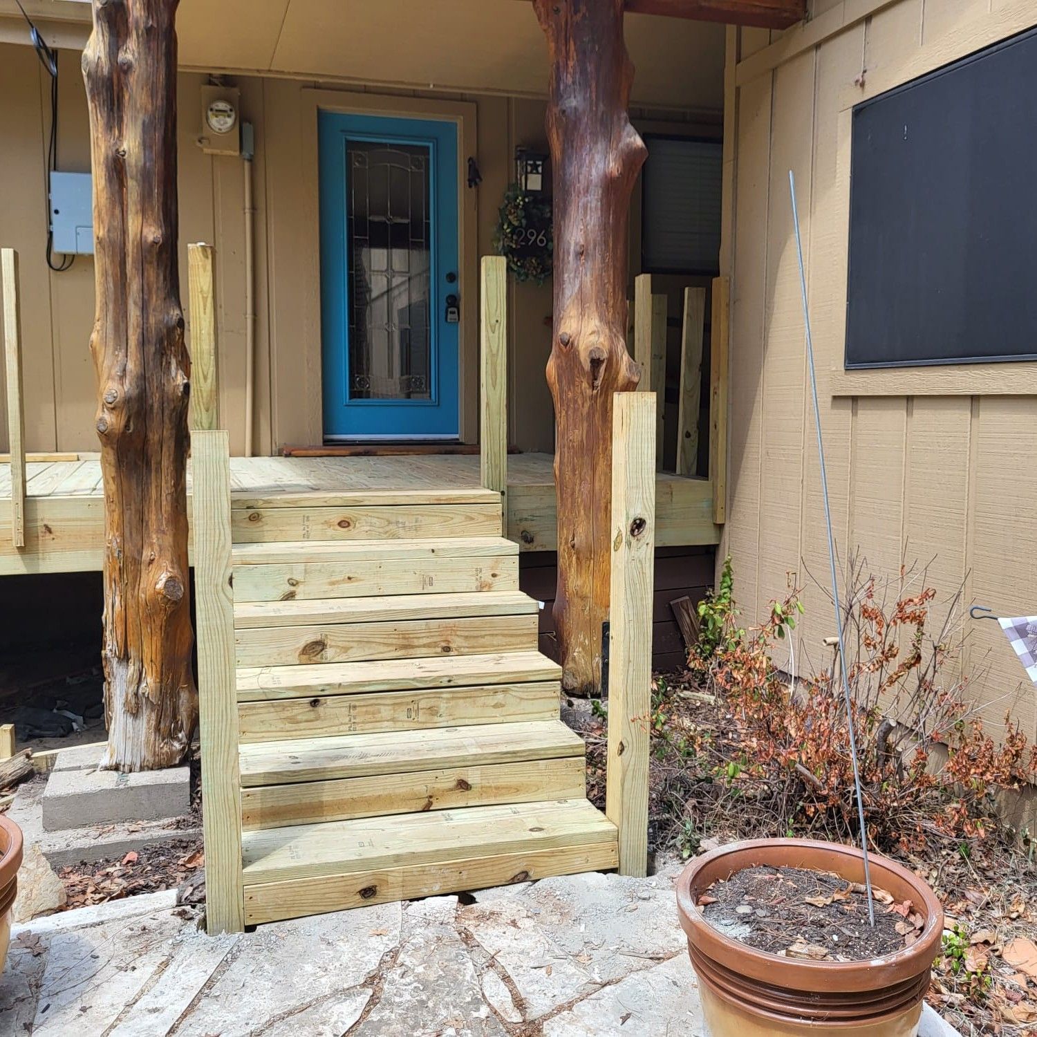 A wooden porch with stairs and a blue door