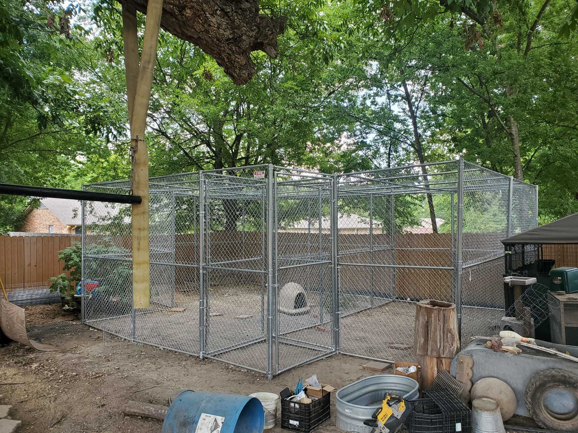 A chain link fence surrounds a dog kennel in a backyard.