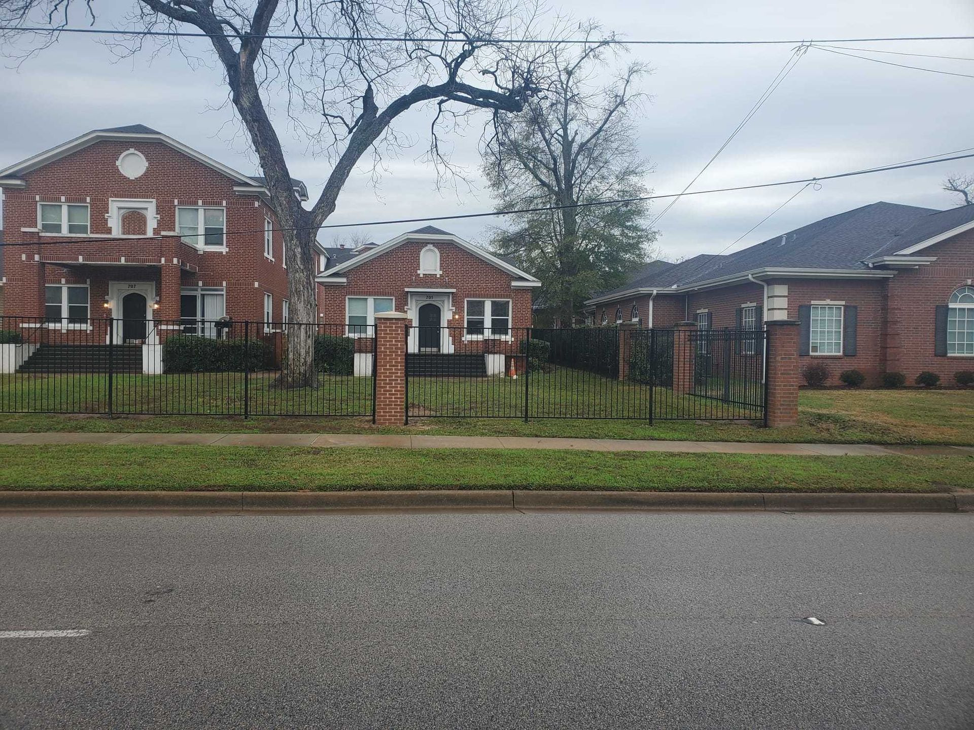 A brick house with a wrought iron fence in front of it