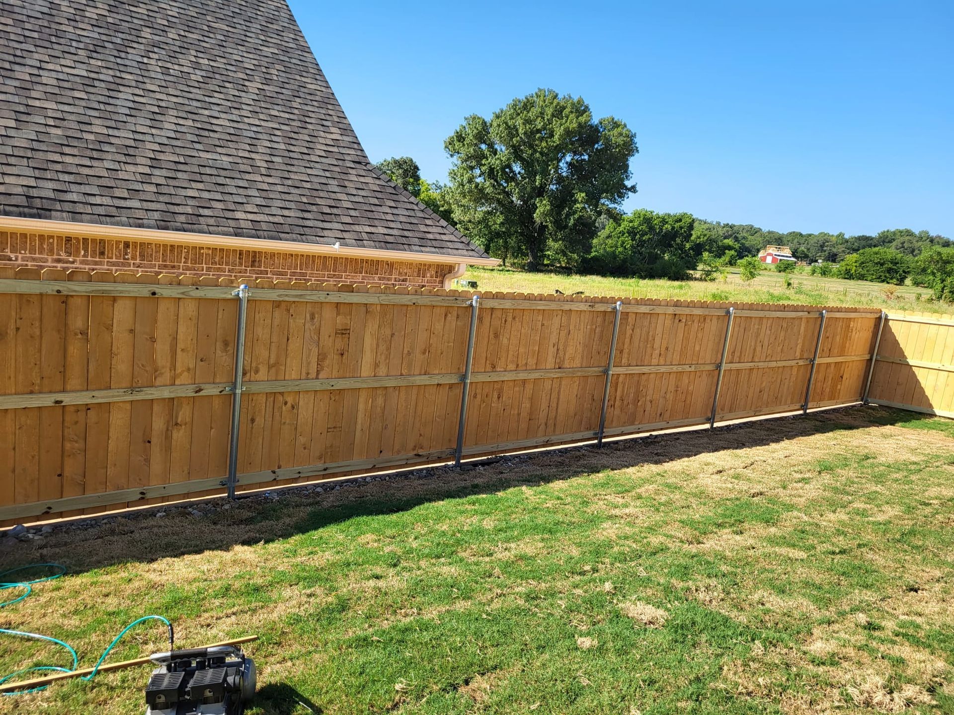 A wooden fence is in the backyard of a house.