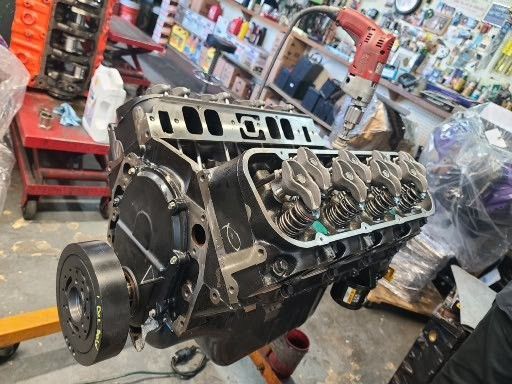 A black engine is sitting on a lift in a garage.