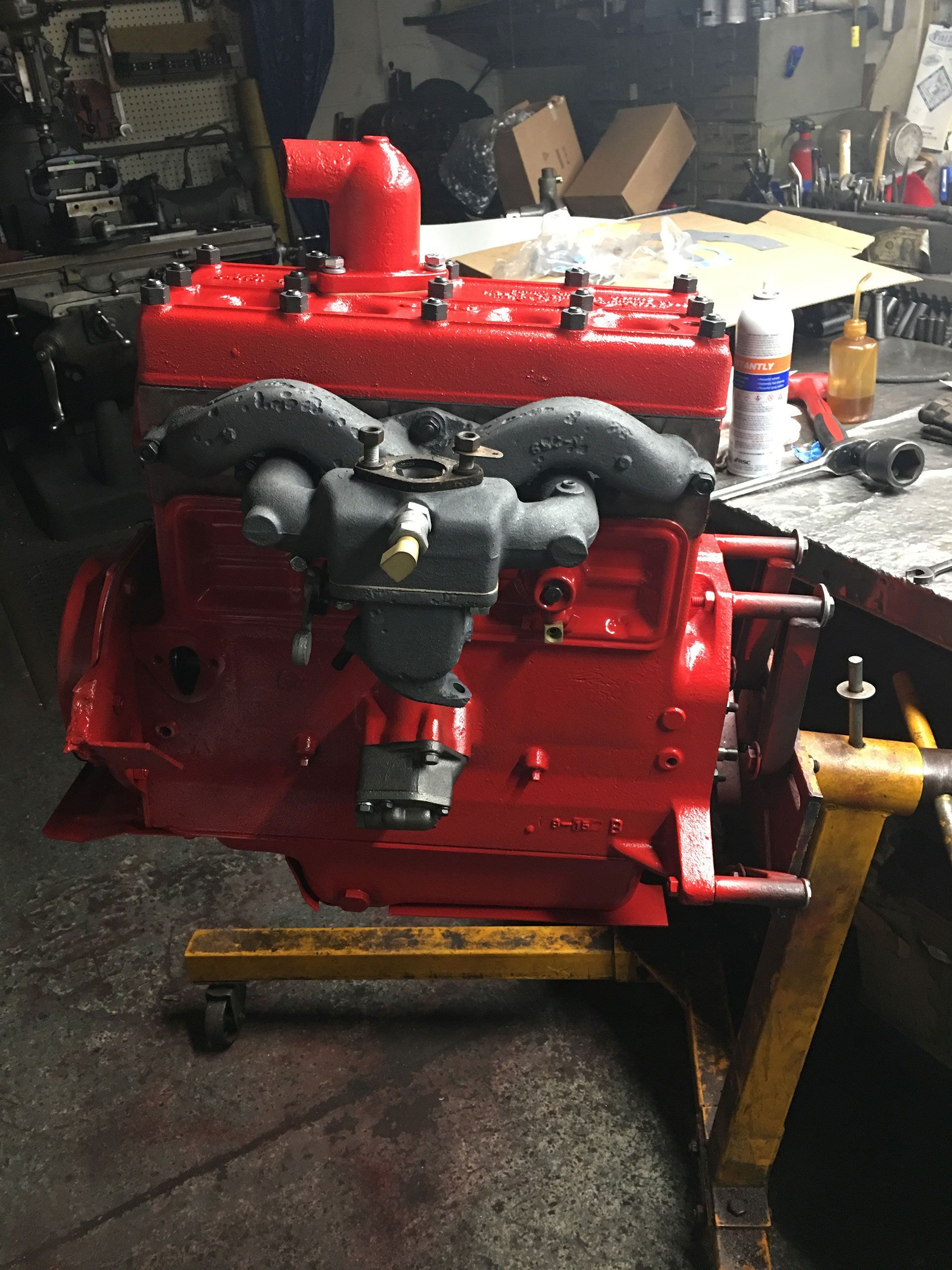 A red car engine on a yellow stand in a garage