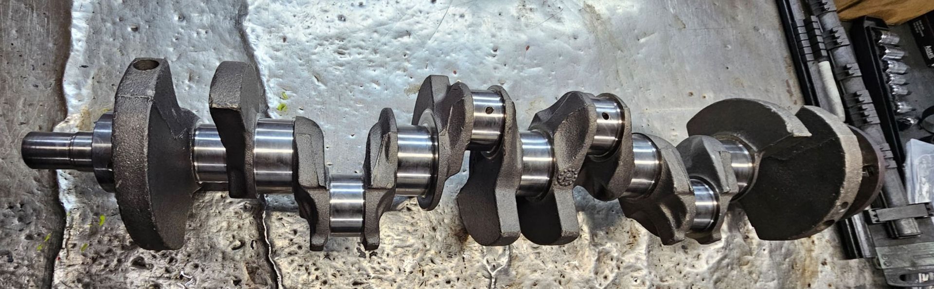 A close up of a crankshaft on a concrete surface.