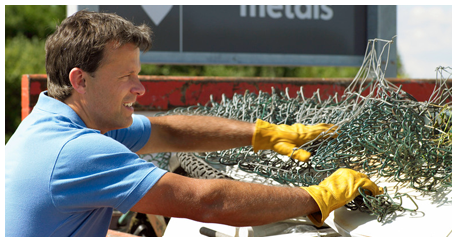 Man with blue shirt and yellow gloves cleaning metal wires