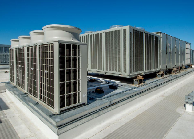Rooftop HVAC units on a white flat roof against a clear blue sky.