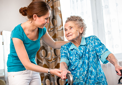 A woman is helping an elderly woman with a walker.