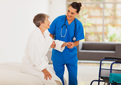 A nurse is helping an elderly woman with her walker.