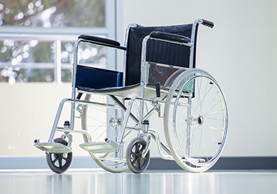 A wheelchair is parked in a hospital hallway next to a window.