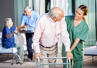 A nurse is helping an elderly man with a walker.