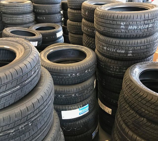Stacks of black car tires piled in a warehouse or tire shop.