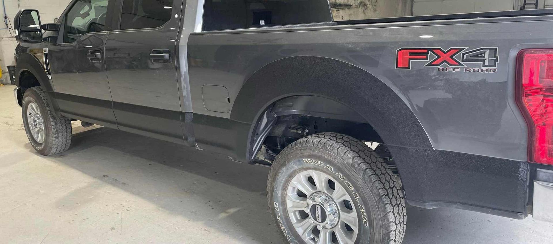 A black ford truck is parked in a garage.