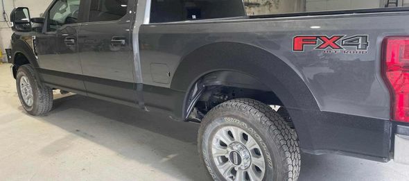 A black ford truck is parked in a garage.