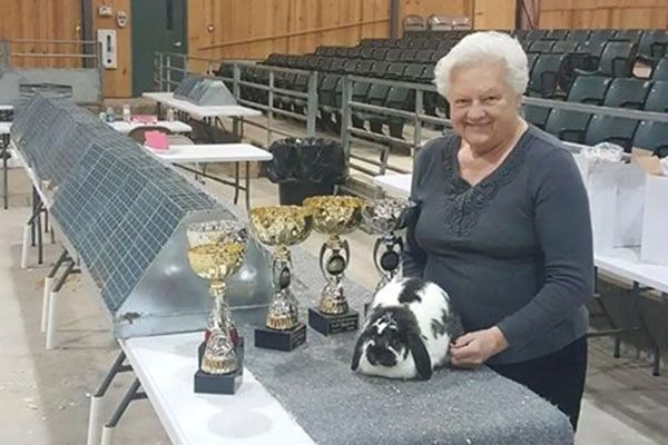 A woman is standing next to a table with trophies on it.