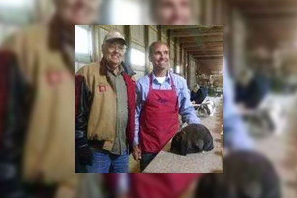 Two men in aprons are standing next to each other.