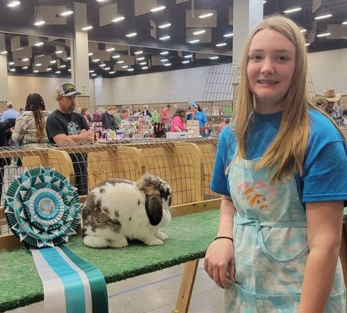 A girl is standing in front of a table with a rabbit on it