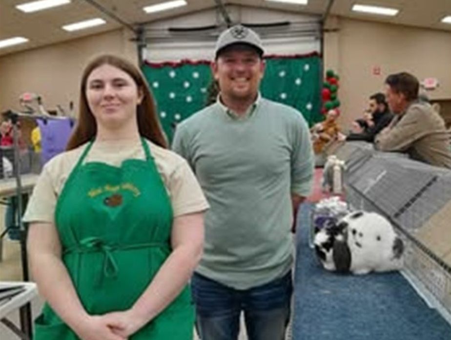 A man and a woman are standing next to each other in front of a rabbit.