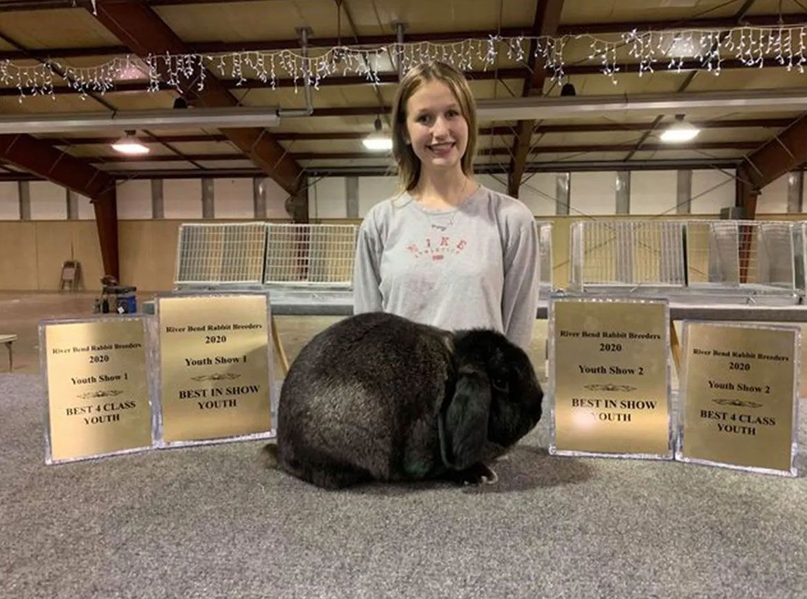 A woman is standing next to a black rabbit.