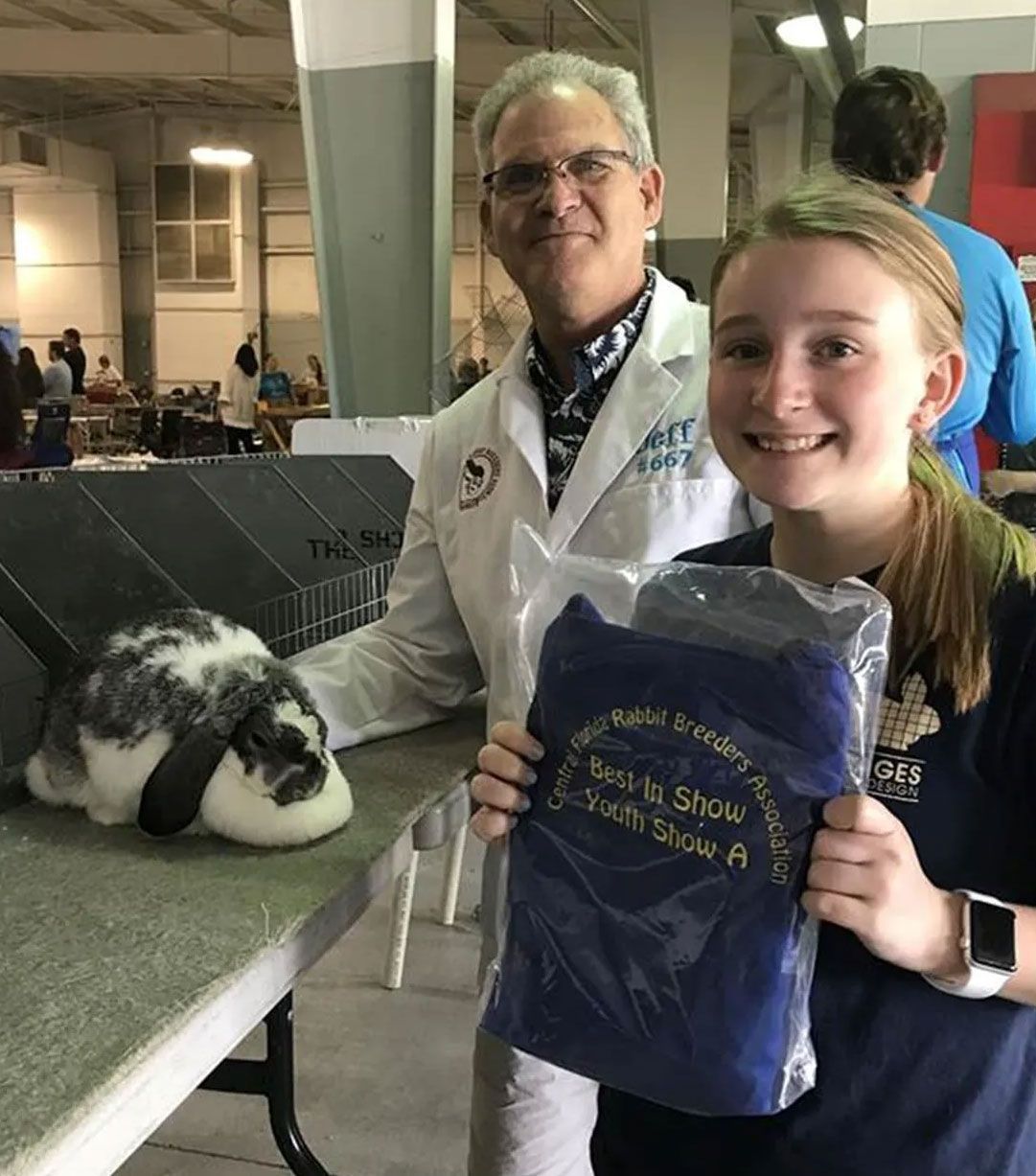 A man and a girl are posing for a picture with a rabbit.
