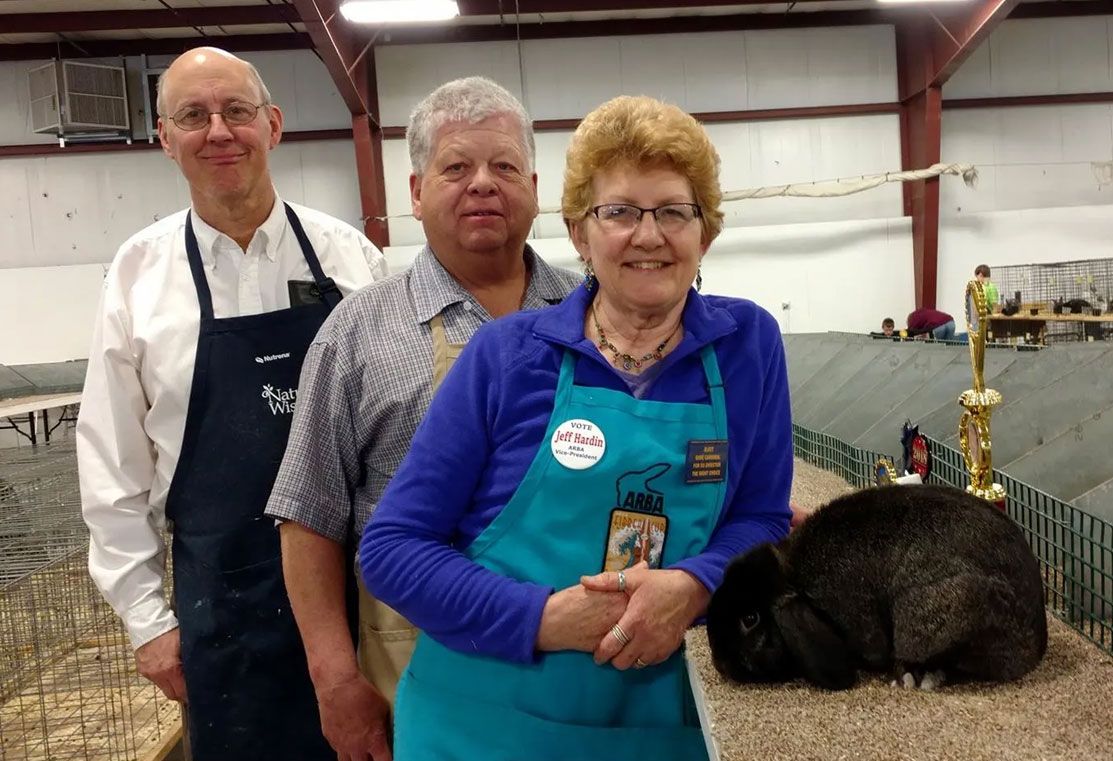 Three people are posing for a picture in front of a rabbit