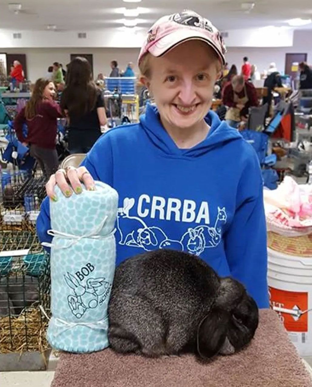 A woman in a blue crrba sweatshirt holds a blanket and a rabbit