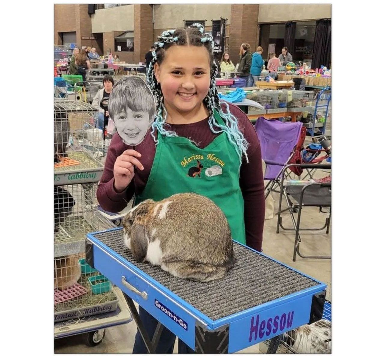 A girl is holding a picture of a boy and a rabbit.