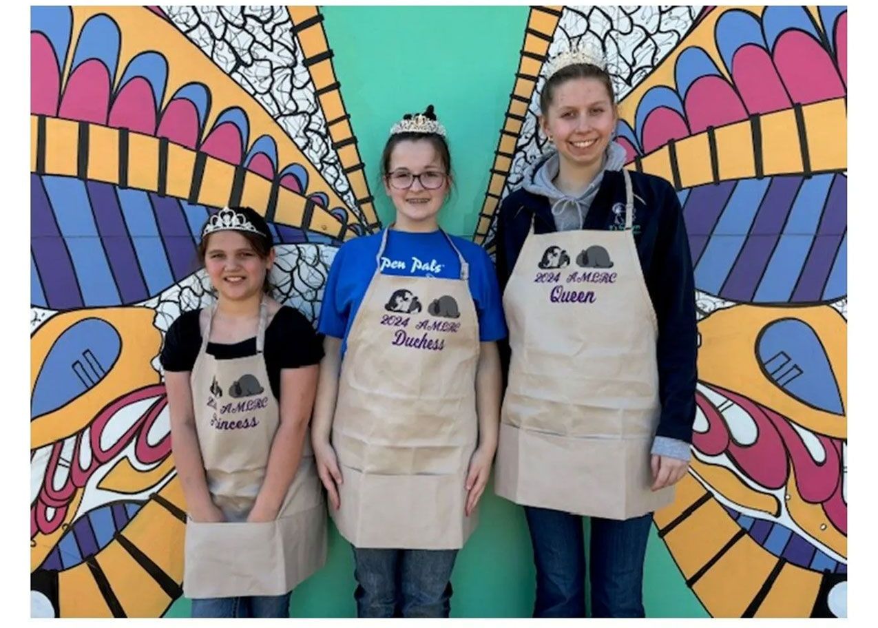 Three women wearing aprons with AMLRC written on them