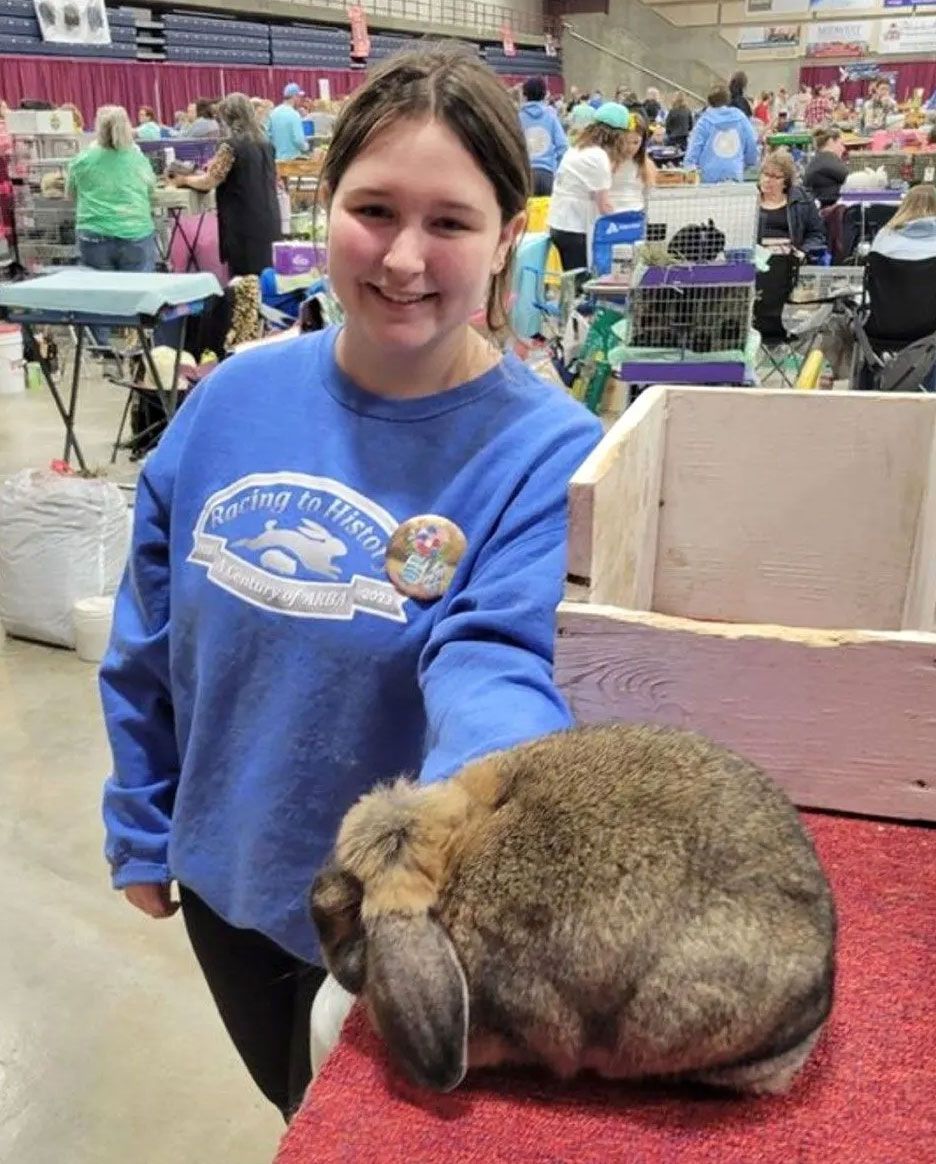 A girl is holding a picture of a boy and a rabbit.