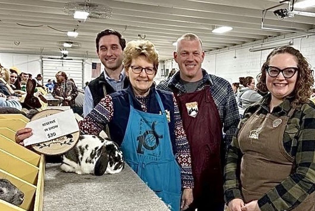 four people pose with a rabbit in a show setting