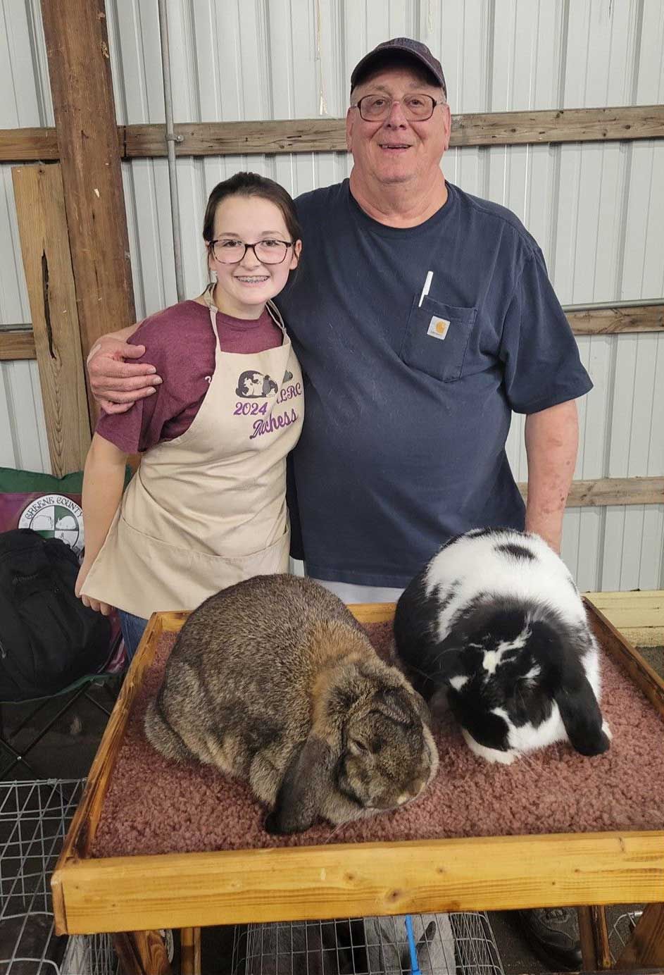 two people stand with two rabbits on a table