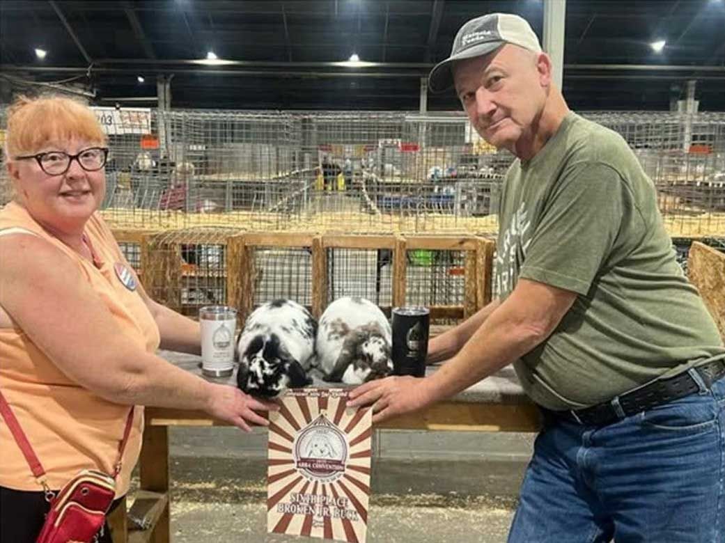 two people hold rabbits at a fair