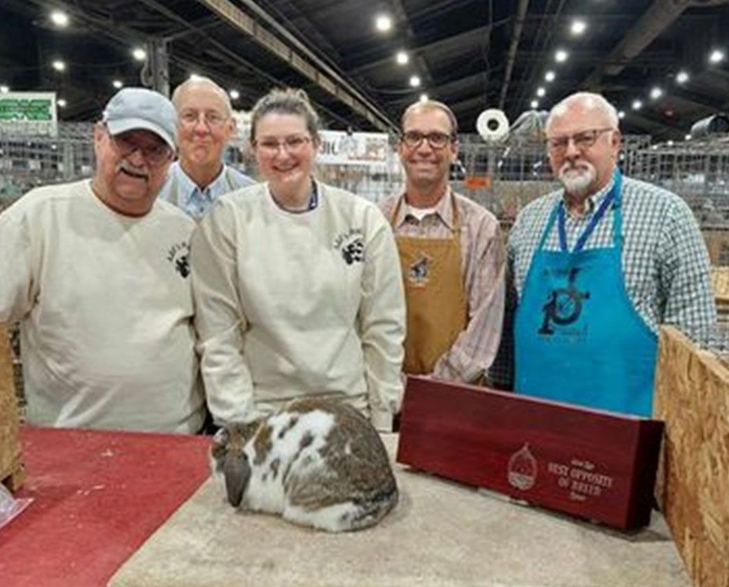 five people with a spotted rabbit and a trophy at an event