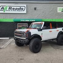 A white ford bronco is parked in front of a building.