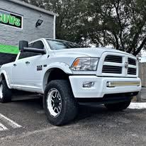 A white truck is parked in a parking lot in front of a building.