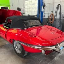 A red jaguar e type convertible is parked in a garage.